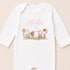 A white onesie with the text "Eodie is one" and illustrations of fairies and butterflies.