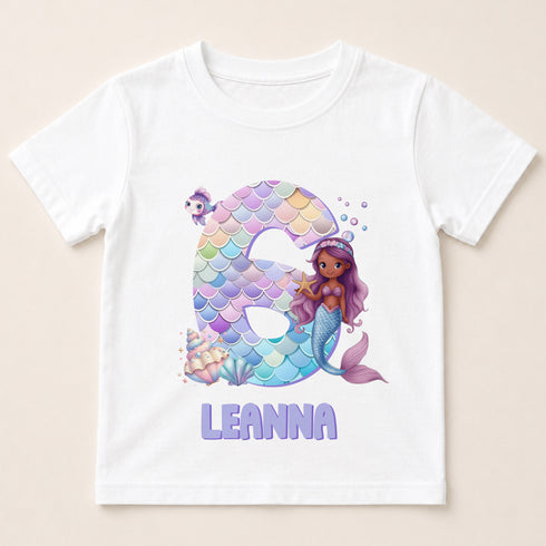 A white t-shirt with a design featuring a mermaid character and the number 6.