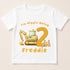 A white t-shirt with a cartoon construction vehicle and the text "I'm Piggin Being 2" printed on it.