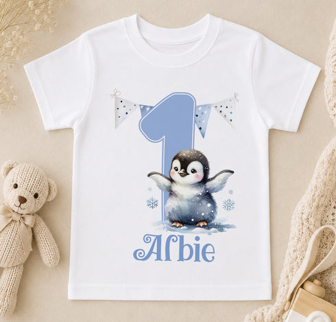 A white t-shirt with a penguin graphic and the number 1, along with the text "Alfie" printed on it.