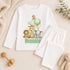 White baby and toddler pyjamas with personalised green safari 1st birthday design, featuring a lion, giraffe, elephant, monkey, balloons, number 1 and child’s name.