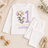 Personalised 1st birthday baby outfit with cute elephant, pastel balloons, purple number 1 and custom name, shown on bib, vest, sleepsuit, t-shirt and white pyjamas.
