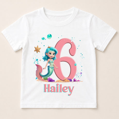A white t-shirt with a mermaid character and the number 6 printed on it, along with bubbles and a starfish. The text "Hailey" is also printed below the mermaid character.