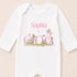 A white onesie with a personalized text and illustrations related to a baby's first birthday.