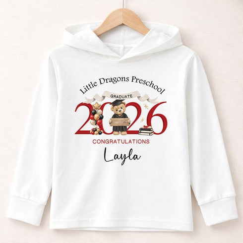 White lightweight hooded long-sleeved T-shirt with a personalised teddy bear preschool graduation 2026 design, displayed on a wooden hanger.