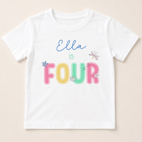 A white t-shirt with the text "Ella is FOUR" printed on it in a colorful, playful font.