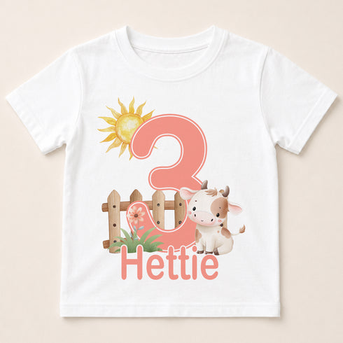 A white t-shirt with a graphic design featuring a cow, a sun, and the number 3.