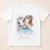 A white t-shirt with a printed design featuring a young girl wearing a crown and hugging a white unicorn. The text below the image reads "Happy Birthday Lucie".