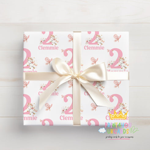A gift box wrapped in pink and white paper with the name 'Clemmie' printed on it, tied with a white ribbon.