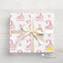 A gift box wrapped in pink and white paper with the name 'Clemmie' printed on it, tied with a white ribbon.