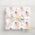 A gift box wrapped with a pink and white pattern featuring a princess and stars, tied with a white ribbon.