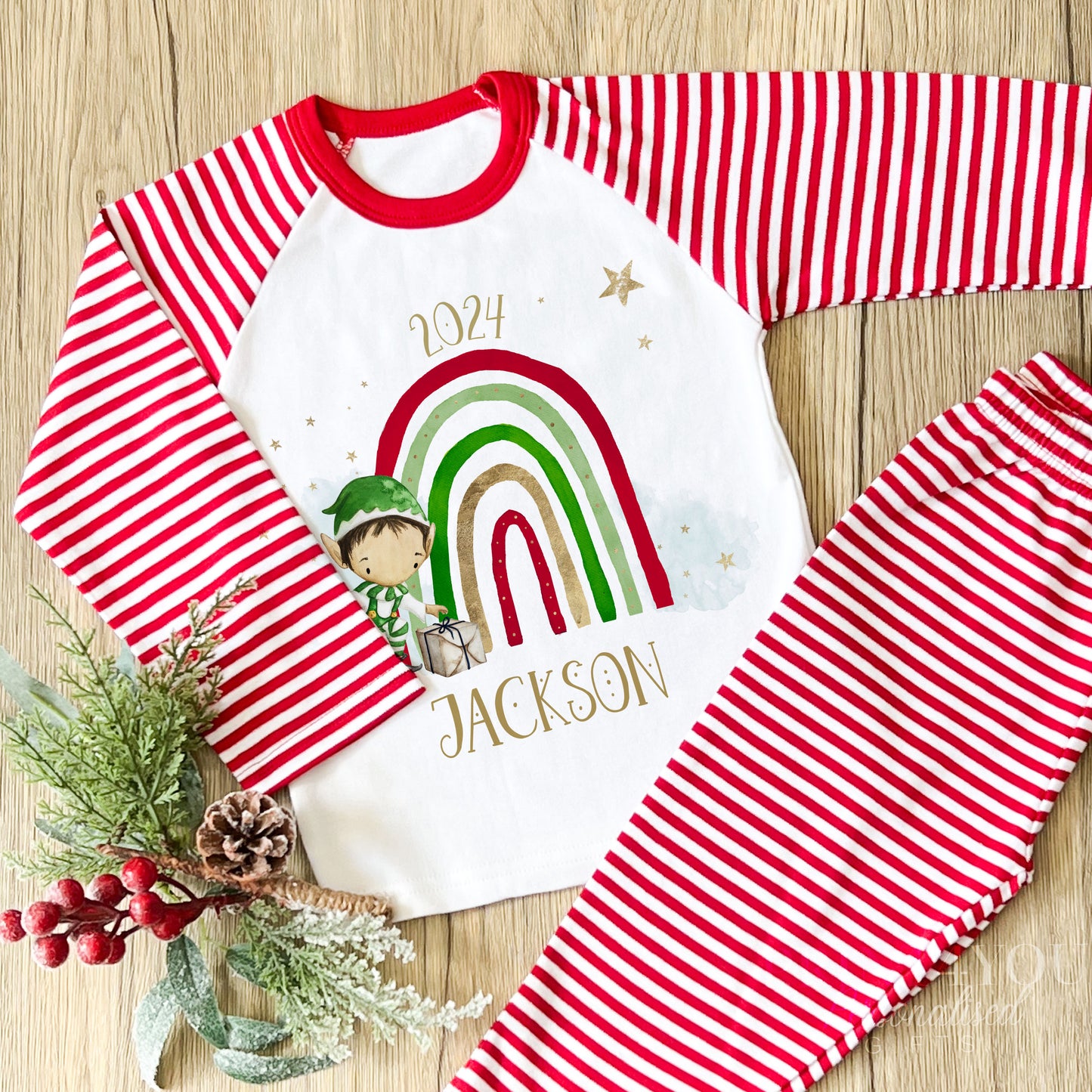 Personalised red and white striped Christmas Eve pyjamas for kids with cheerful Rainbow Elf design and custom name printed on the front
