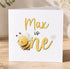 A white greeting card with a cartoon bee and the text "Max is one" printed on it.