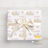 A gift box wrapped with a white ribbon and featuring a repeating pattern of butterflies and the name "Amelia" printed on it.