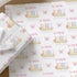 a set of gift wrapping paper with a repeating pattern of the word "Amelia" and butterflies. The wrapping paper is placed on a wooden surface, with some white flowers visible in the background.
