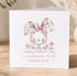 A white greeting card with a cute bunny wearing a pink bow and surrounded by flowers, with the text "Happy Mother's Day To my wonderful mummy Love from Amelia" printed on it.