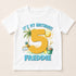 A white t-shirt with a graphic design featuring a large number 5, a palm tree, a beach scene, and a bucket. The text above the number reads "It's my birthday!" and below the number is the name "FREDDIE".