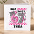 A birthday card with a pink and black checkered design, featuring the number 67 and the text "I WAS NOW I'M THEA"