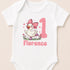 A white baby onesie with a cartoon image of a duck wearing a pink bow and the name "Florence" printed on it.