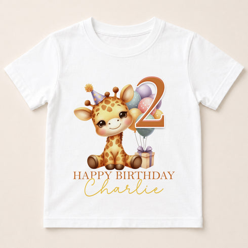 A white t-shirt with a cartoon image of a giraffe wearing a party hat and surrounded by balloons, along with the text "Happy Birthday Charlie".