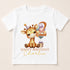 A white t-shirt with a cartoon image of a giraffe wearing a party hat and surrounded by balloons, along with the text "Happy Birthday Charlie".
