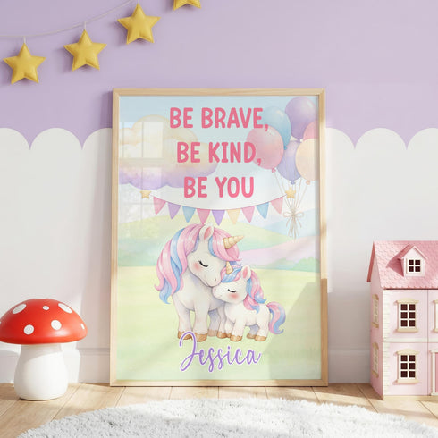 a framed poster with a unicorn and a message encouraging bravery, kindness, and self-confidence. The poster is displayed in a room with a pink and purple color scheme, and there are small toy houses and a mushroom nearby.