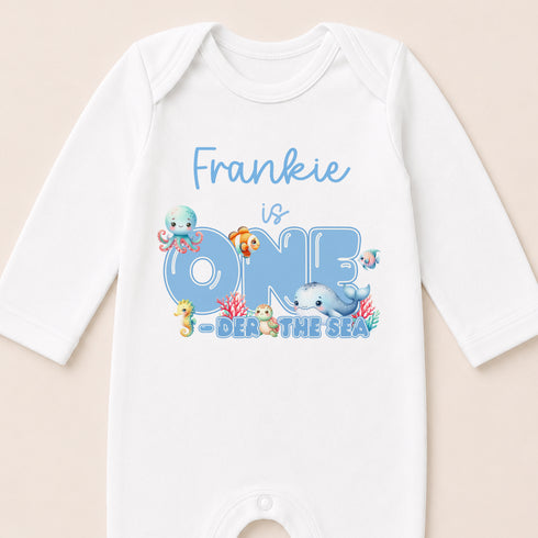 A white onesie with a personalized text and illustrations related to the ocean theme.
