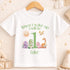 A white t-shirt with a graphic design featuring a sun, a dragon, and various animals, along with the text "When I wake up I will be 1 Luke".