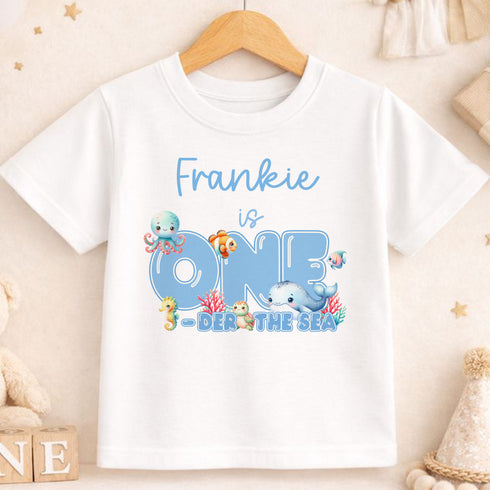 A white t-shirt with a personalized text and illustrations related to a child's birthday theme.