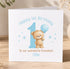 A white greeting card with a teddy bear and a blue balloon, celebrating a first birthday.