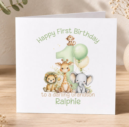 A personalized first birthday card featuring a cartoon illustration of a lion, giraffe, and elephant, along with the number 1 and the text "Happy First Birthday to a lovely Grandson Ralphie".