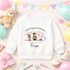 White children’s sweatshirt featuring a personalised pink 2026 teddy bear preschool graduation design with a nursery name and child’s name.