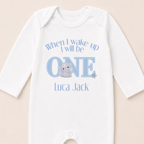 A white onesie with a blue elephant and text that says "When I wake up I will be ONE Luca Jack" printed on it.