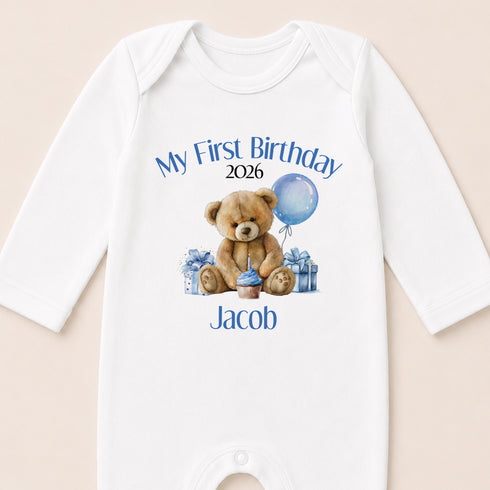 A white onesie with a teddy bear and a blue balloon, along with the text "My First Birthday Jacob" printed on it.