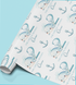 a roll of wrapping paper with a repeating pattern of blue whale illustrations and anchors.