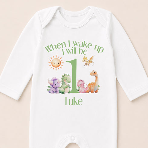 A white onesie with a personalized message and illustrations of various animals, including a sun, dragon, and dinosaur, printed on it.