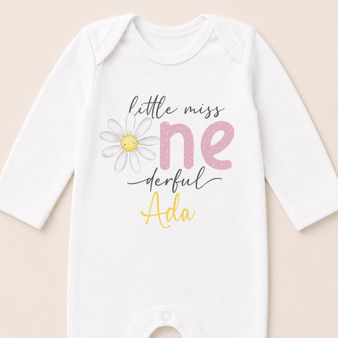 A white onesie with a flower design and text printed on it.