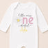 A white onesie with a flower design and text printed on it.