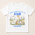 A white t-shirt with a printed design featuring a giraffe, elephant, lion, and other animals in a grassy field with clouds in the background. The text on the t-shirt says "When I wake up I will be FOUR KADIEN".