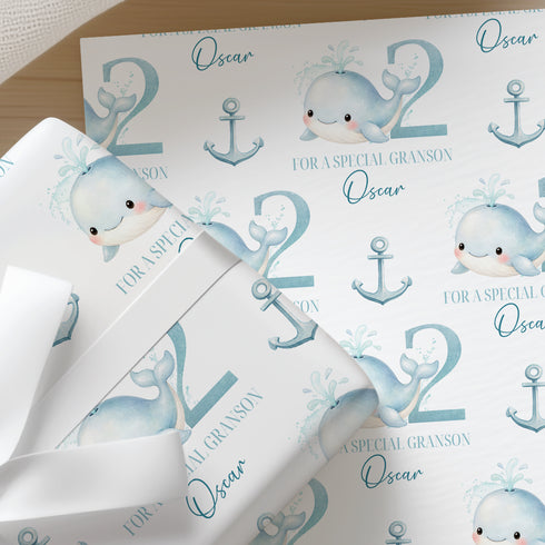a repeating pattern of cartoon-style illustrations of a whale and an anchor, along with the text "Oscar" and "2" printed on the wrapping paper.