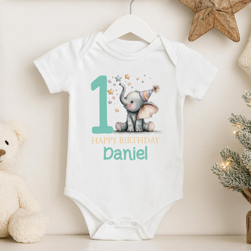 Personalised 1st birthday baby outfit with cute elephant, party hat, stars, teal number 1 and custom name, shown on bib, vest, sleepsuit, t-shirt and white pyjamas.