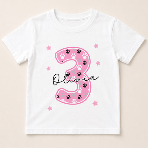A white t-shirt with a pink number 3 and paw prints design, along with the name "Olivia" written below it.