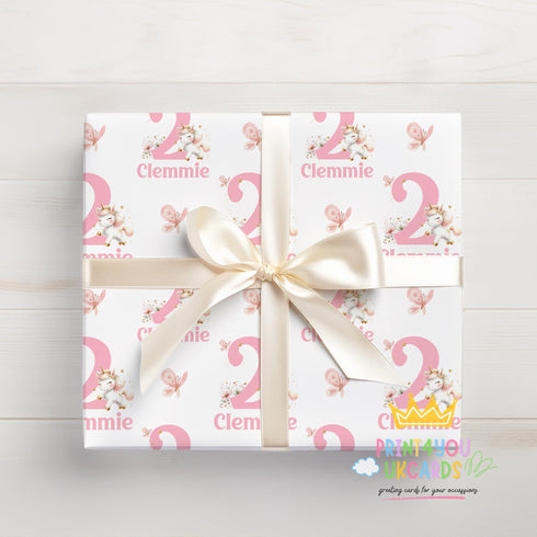 A gift box wrapped in pink and white paper with the name 'Clemmie' printed on it, tied with a white ribbon.