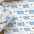 a set of wrapping paper with a repeating pattern of the name "Oliver" and illustrations of fish, including a clownfish, against a blue background. The wrapping paper is displayed on a wooden surface, with some white flowers visible in the background.