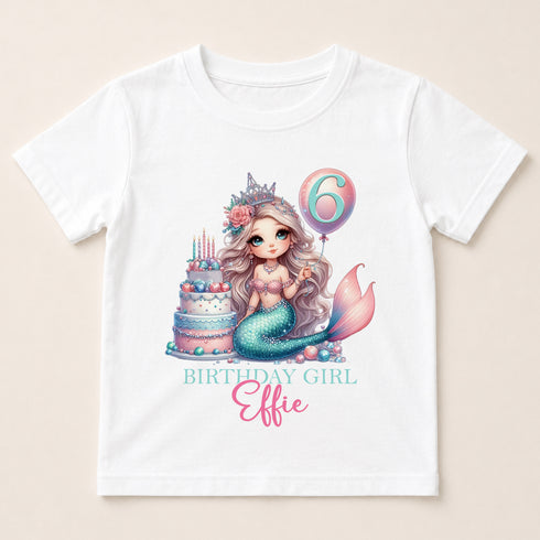 A white t-shirt with a graphic design featuring a mermaid character and a birthday cake.