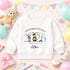 White children’s sweatshirt featuring a personalised blue 2026 teddy bear preschool graduation design with a nursery name and child’s name.