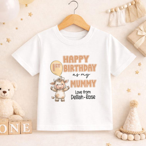 May include: White short-sleeved t-shirt featuring a cartoon cow holding a balloon. The text reads "HAPPY 1ST BIRTHDAY as my MUMMY" and "Love from Delilah-Rose". The shirt is displayed on a wooden hanger.