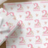 a set of wrapping paper and a gift box with a pink and white floral pattern, along with some white flowers in the background.