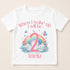 A white t-shirt with a colorful graphic design featuring a rainbow, clouds, and butterflies. The text on the t-shirt says "When I wake up I will be 2 Amelia".