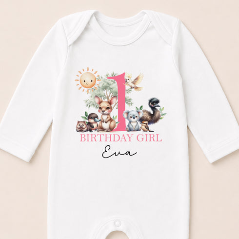 A white onesie with a pink number 1 and various animal illustrations, along with the text "BIRTHDAY GIRL Eva".